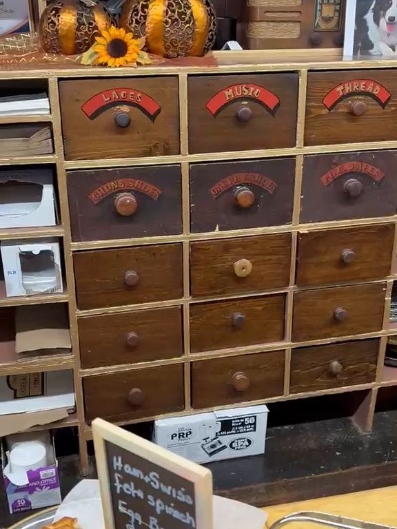 A wall of original wooden store drawers with brass pulls