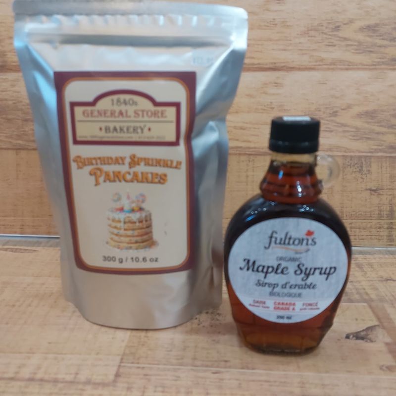 A bag of the store’s own pancake mix beside a bottle of maple syrup